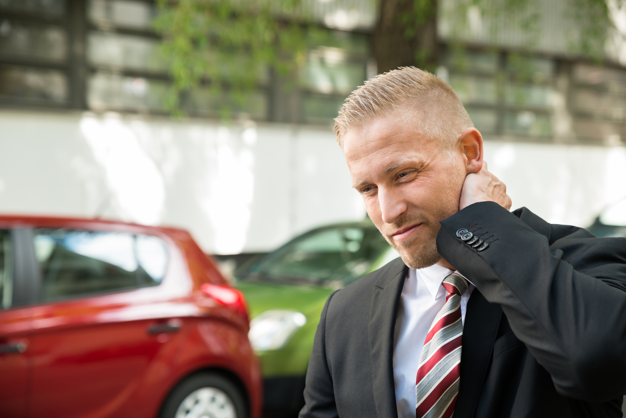 A man in a suit is touching his neck.